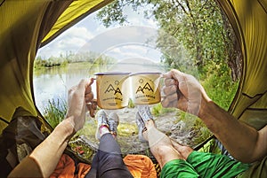 Young couple sitting in the tent and drinking tea while looking on the Desna river