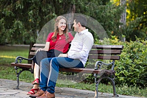 Young couple sitting together on a bench in the park