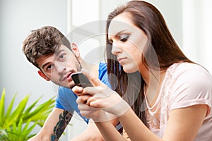 Young couple sitting using a mobile phone with focus to the man