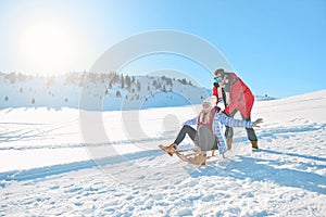 Young Couple Sledding And Enjoying On Sunny Winter Day