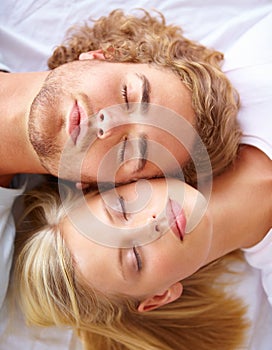 Rest and relaxation. A young couple sleeping in bed with their heads together.