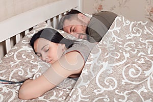 Young couple sleeping in bed under blanket.