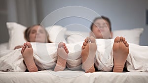 Young couple sleeping in bed, view of healthy feet, antifungal spray effect
