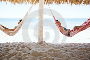 Young couple sleeping in hammocks at the beach