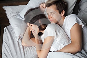 Young couple sleeping together embracing lying asleep on comfort