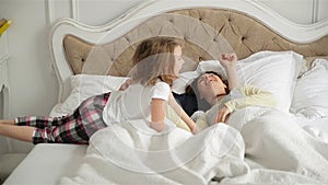 Young Couple is Sleeping Together Hugging in the Bed at Home. Active Little Girl is Waking Her Sleeping Parents up.