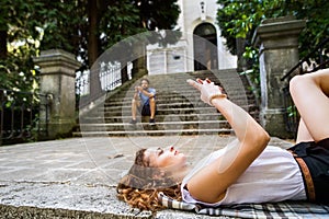 Young couple with smartphones on stairs in town.