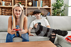 Young couple smiling happy playing video game and using smartphone at home