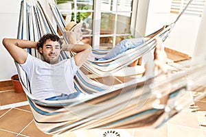 Young couple smiling happy relaxed with hands on head lying on hammock at terrace