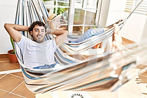 Young couple smiling happy relaxed with hands on head lying on hammock at terrace