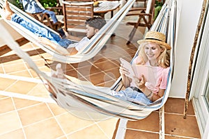 Young couple smiling happy relaxed using smartphone and reading book