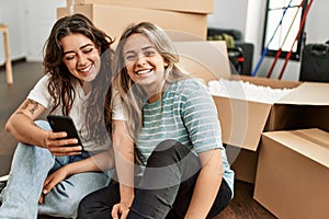 Young couple smiling happy using smartphone at new home