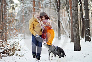 Young couple smiling and having fun in winter park with their husky dog