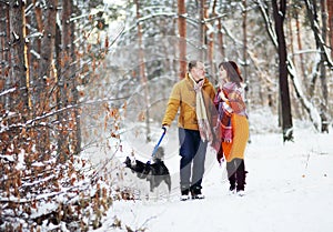 Young couple smiling and having fun in winter park with their husky dog