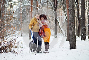 Young couple smiling and having fun in winter park with their husky dog