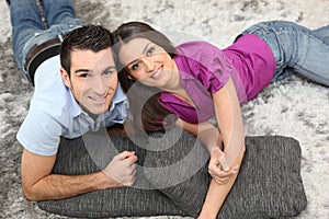 Young couple smiling laid on cushions