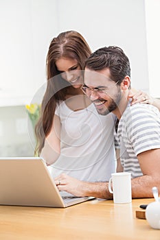 Young couple smiling and using laptop