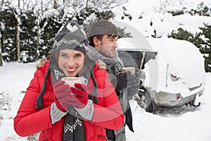 Young couple in snow with car