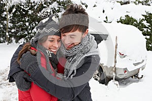 Young couple in snow with car