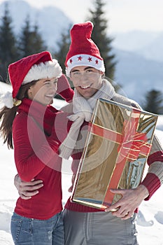 Young couple on the snow with Christmas gift