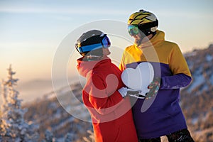 A young couple with a snowy heart in their hands against the background of a winter landscape in the ski resort