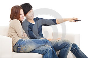 Young couple on sofa watching TV with remote control