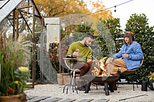 Young couple spending dinner time by the fire at backyard