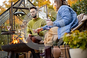 Young couple spending dinner time by the fire at backyard