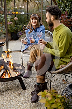 Young couple spending dinner time by the fire at backyard