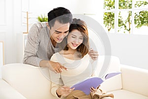 Young couple spending time reading together on sofa