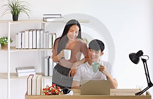 Young couple spending time together at home office drinking coffee while working online from home