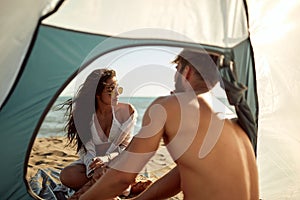 Young couple spending wonderful time together while camping on the beach at sea. Summer, vacation, sea