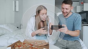 Young couple sport fans watching football match at home and cheering team. Happy friends with pizza watching soccer game