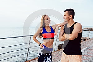 Young couple in sportswear standing on the pier near the sea