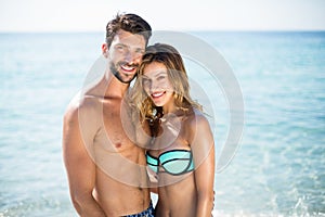 Young couple standing with arm around on shore at beach