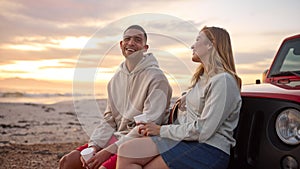 Young Couple Standing Chatting By Car With Hot Drink At Beach Watching Sunrise Together photo