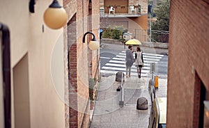 A young couple is standing on the crosswalk while walking the city on a rainy day. Walk, rain, city, relationship