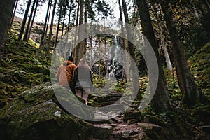 Young couple standing in front of a waterfall in the forest