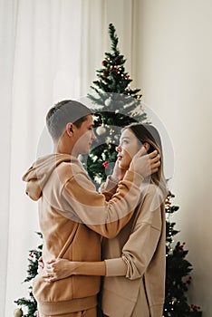 Young couple standing at home near Christmas tree