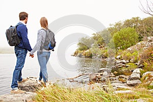 Young couple standing by a lake admiring the view photo