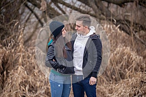 Young couple standing in nature on a winter day, looking at each other