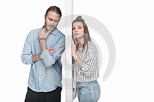 Young couple standing separated by wall isolated on white