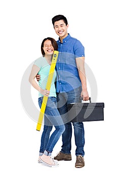 Young couple standing with spirit level measuring tool and tool box