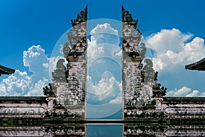 Young couple standing in temple gates and holding hands of each other at Lempuyang Luhur temple in Bali, Indonesia. Vintage tone