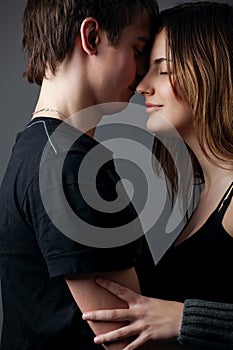 Young couple standing together against a grey wall