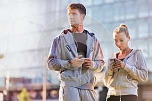 Young couple standing while using smartphone after working out