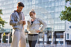 Young couple standing while using smartphone after working out