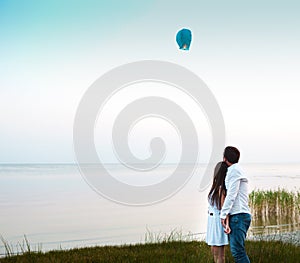 Young couple start a green Chinese sky lantern in the dusk