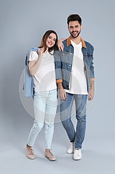 Young couple in stylish jeans on grey