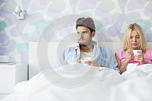 Young couple suffering from cold while relaxing in bed at home